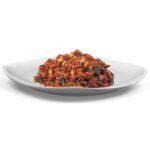Primo piatto pronto Riso rosso con verdura su piatto, preparato con riso rosso e mix di verdure dell'orto e arachidi. Dieta vegetariana e vegana