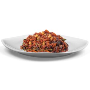 Primo piatto pronto Riso rosso con verdura su piatto, preparato con riso rosso e mix di verdure dell'orto e arachidi. Dieta vegetariana e vegana